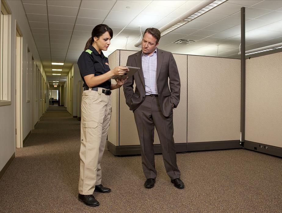 Two people standing, on the left is a SERVPRO representative, on the right is a business professional. Both discussing plans.